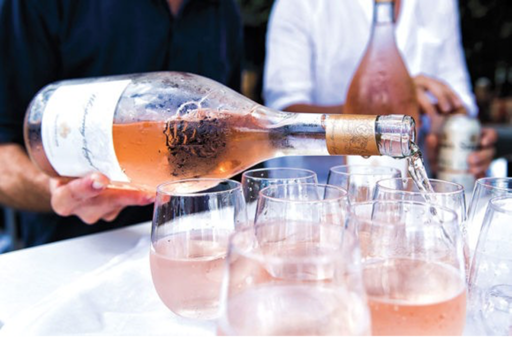 Someone pouring Provençal Chateau d’Esclans, rosé wine into glasses on a table.
